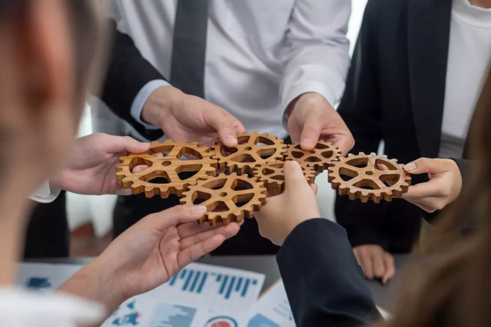 closeup-top-view-hands-holding-gears-table-with-bi-reports-harmony