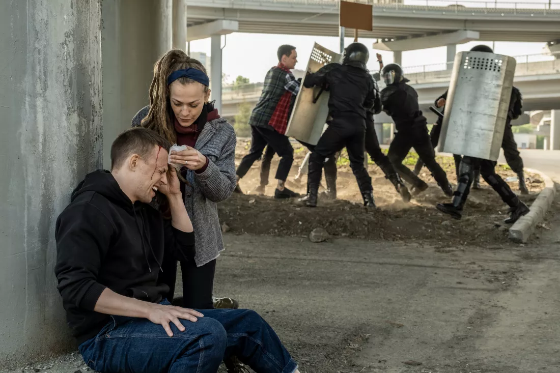 serious-young-woman-giving-first-aid-rebel-suffered-from-fight-with-riot-police-girl-stopping-bleeding-victim-riot