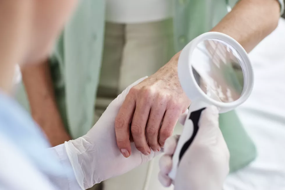 close-up-doctor-holding-magnifying-glass-examining-hands-senior-woman